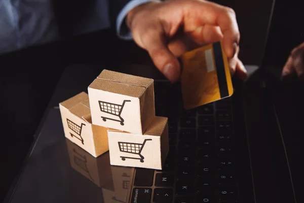 Boîtes dans un chariot sur un clavier d'ordinateur portable. Idées sur les achats en ligne, achats en ligne est une forme de commerce électronique qui permet aux consommateurs d'acheter directement des marchandises auprès d'un vendeur sur Internet. — Photo