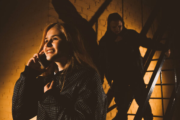 Silhouette of a man attacks a woman from behind in a dark tunnel. Violence against women concept. copy space