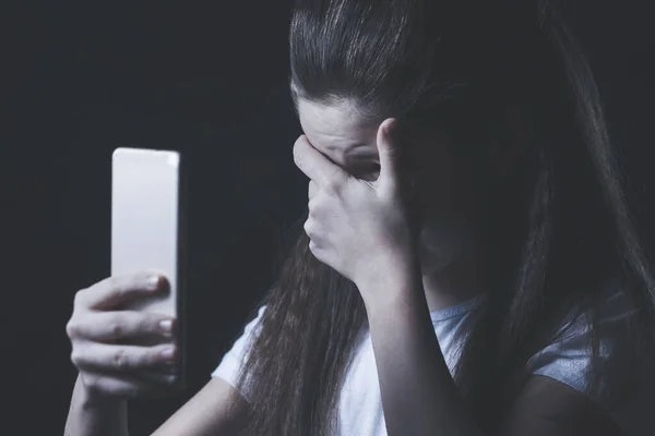 Mladé děvče nešťastné zranitelných pomocí mobilního telefonu, strach a zoufalství, utrpení online zneužívání cyberbullying je pronásledován — Stock fotografie