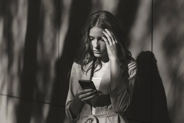 Unglückliche junge Frau mit Smartphone-Porträt. trauriges Mädchen, das schlechte Nachrichten liest oder mit dem Handy SMS schreibt. Familienangelegenheiten, Problemkonzept — Stockfoto