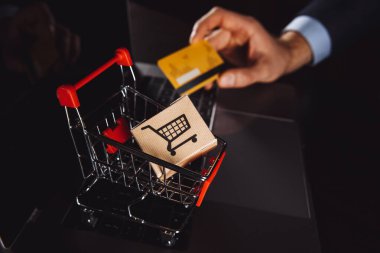 Dizüstü bilgisayarın klavyesindeki tramvayda kutular. Çevrimiçi alışveriş, çevrimiçi alışveriş, tüketicilerin internet üzerinden doğrudan mal satın almalarına olanak sağlayan bir tür elektronik ticarettir..