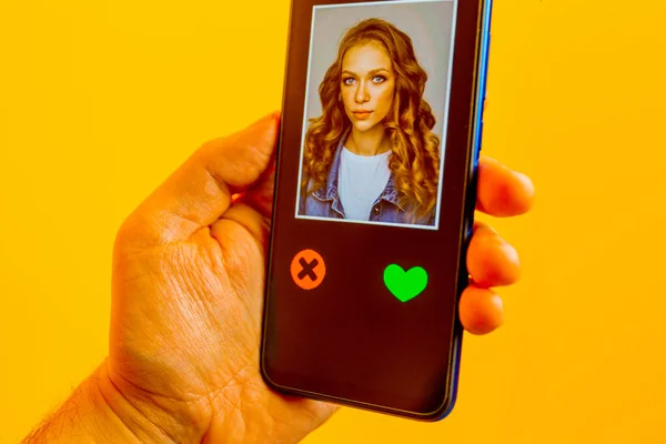 Online dating app in smartphone. Man looking at photo of beautiful woman. Person swiping and liking profiles on relationship site or application. Single guy searching for love partner. Mockup website.
