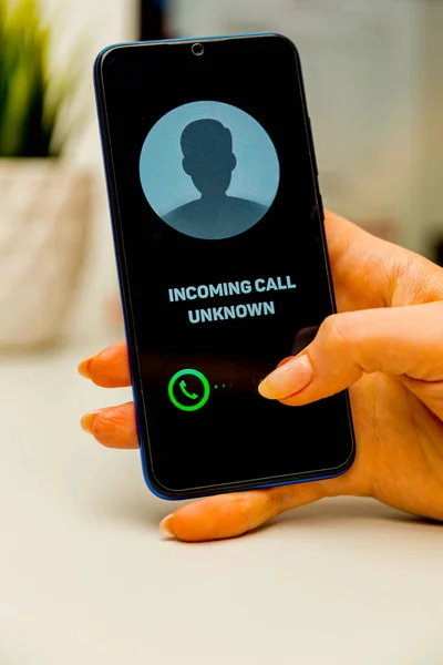 Unknown caller. A man holds a phone in his hand and thinks to end the call. Incoming from an unknown number. Incognito