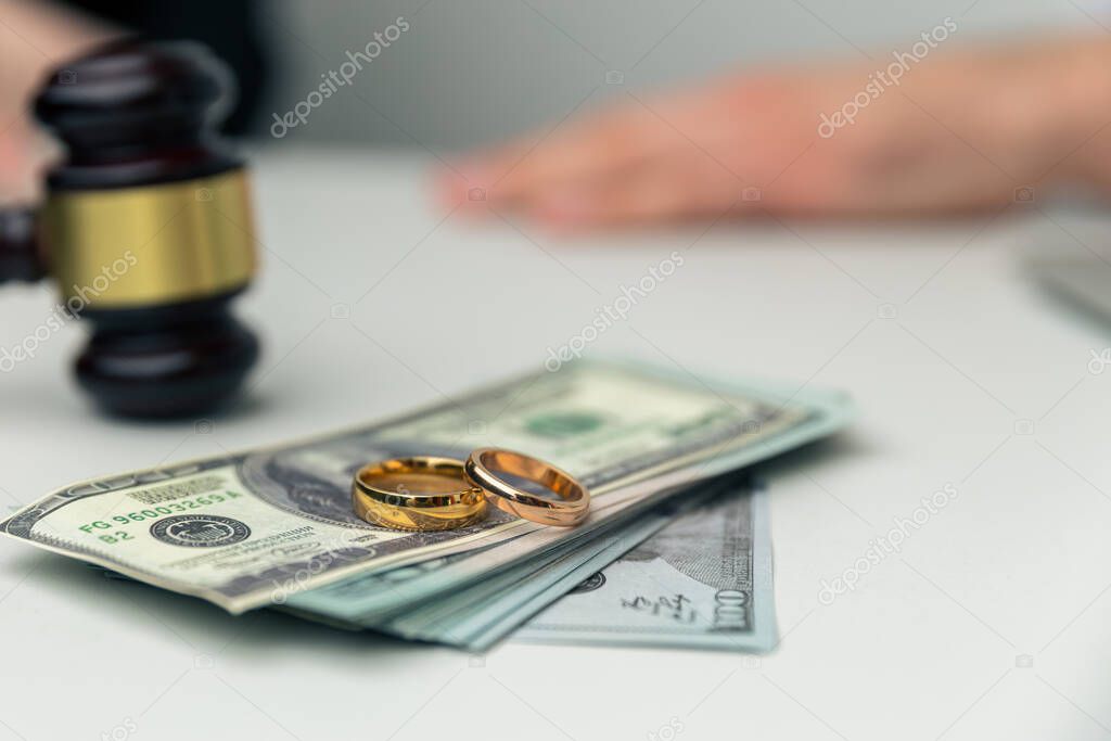 Divorce property. Money and wedding rings on the table.