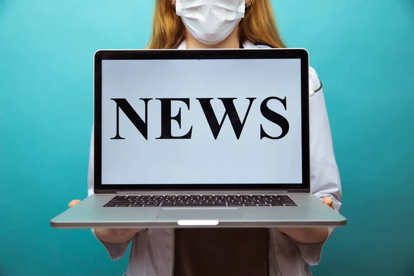 Medical news. Woman therapist in glasses holding laptop standing at the blue wall.