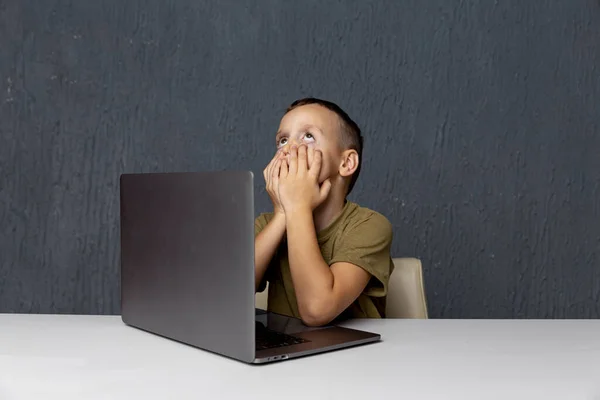 Thuis leren in quarantaine. Droevige jongen zit in de kamer naast de laptop. — Stockfoto