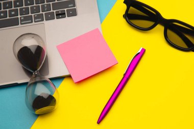 En az çalışma alanı - Çalışma masasının dizüstü bilgisayarı, klavyesi, kalemi ve kum saati olan yaratıcı düz yatay fotoğrafı