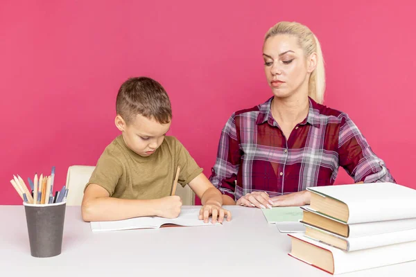 Tarefa de casa à distância com a mãe em casa no momento da quarentena. Menino com a mãe sentada na mesa e estudando . — Fotografia de Stock