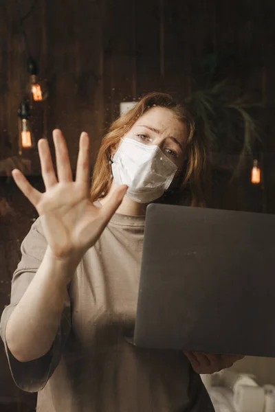 Quarantine stay at home. Bored and worried woman working alone at home in the medicine mask.