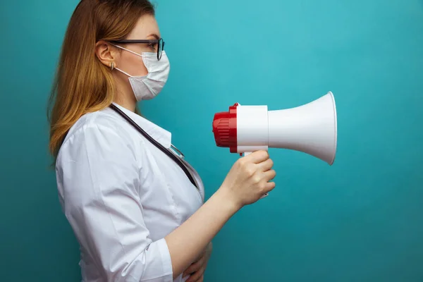 Female doctor in protection suit and glasses with mask holds megaphone — Stock Photo, Image