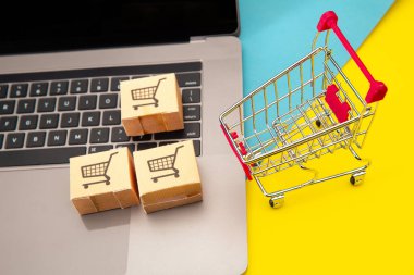 İnternetten alışveriş - Klavyede alışveriş arabası logosu olan kağıt karton ya da paket. İnternet üzerinden alışveriş hizmeti sunuyor.