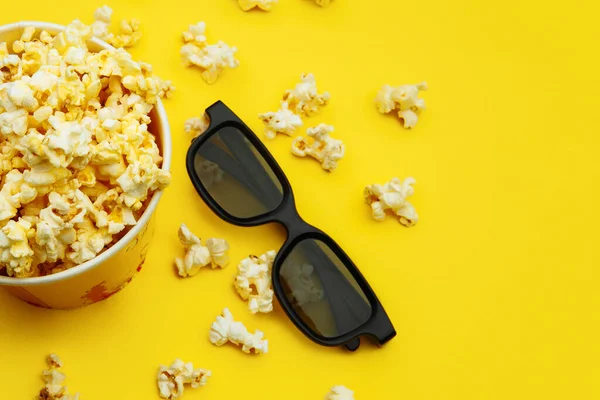 Popcorn in una ciotola e bicchieri 3d su sfondo giallo, vista dall'alto — Foto Stock