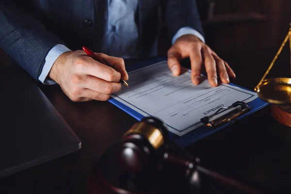 Muž právník pracující s papírovou smlouvou. Dřevěný kladívko a libra na stole. — Stock fotografie