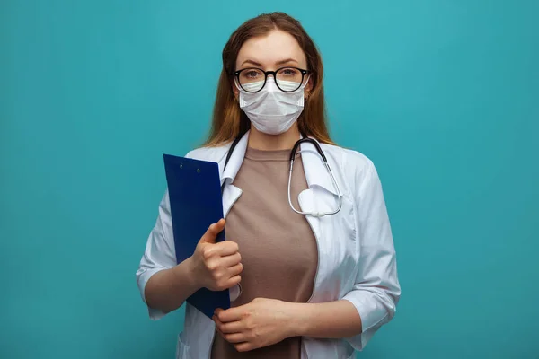 Young doctor with clipboard on blue background. Space for text — Stock Photo, Image