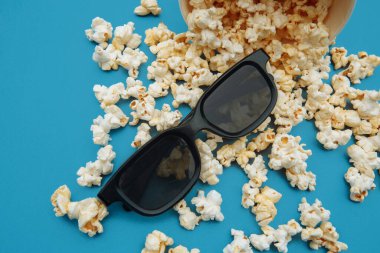 Kaseden patlamış mısır döküldü. Filmi izlemek için gözlük mavi arka planda.