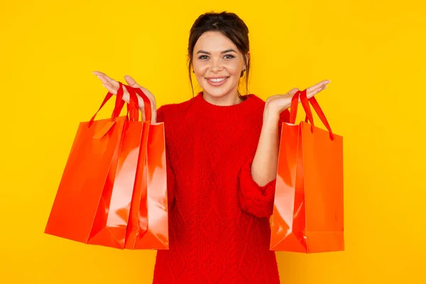 Nakupování online koncept. Šťastná žena s velkými taškami stojí izolované ve žlutém studiu. — Stock fotografie