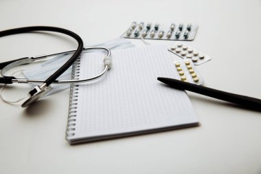 Doktorlar Günü konsepti, steteskop, maske, ilaç ve not defteri doktor masasında ya da hemşire masasında. Sağlık kontrolü ya da sağlık sigortası konsepti. Tıbbi sağlık geçmişi