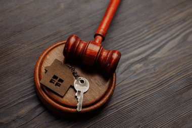 Judge gavel and key chain in shape of two splitted part of house on wooden background. Concept of real estate auction or dividing house when divorce, division of property, real estate, law system clipart