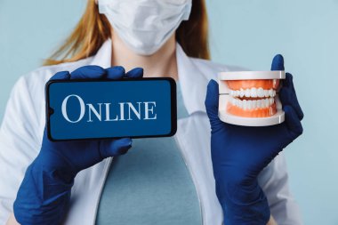 Portrait of beautiful female dentist posing in dental clinic holding smartphone with green screen and presenting mobile app or website to camera, copy space clipart