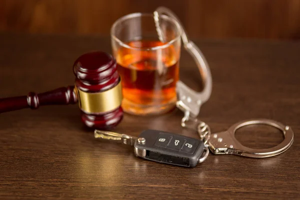 Виски с ключами от машины и наручниками. Концепция вождения в пьяном виде — стоковое фото