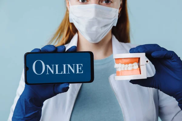 Portrait d'une belle dentiste posant dans une clinique dentaire tenant un smartphone avec écran vert et présentant une application mobile ou un site Web à la caméra, copiez l'espace — Photo