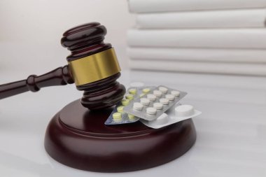 Drugs and law. Judge gavel and colorful pills on a wooden desk, dark background, closeup view clipart