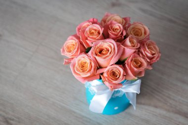 pembe-turuncu gül turkuaz bir kutu içinde bir yay ile bağlı