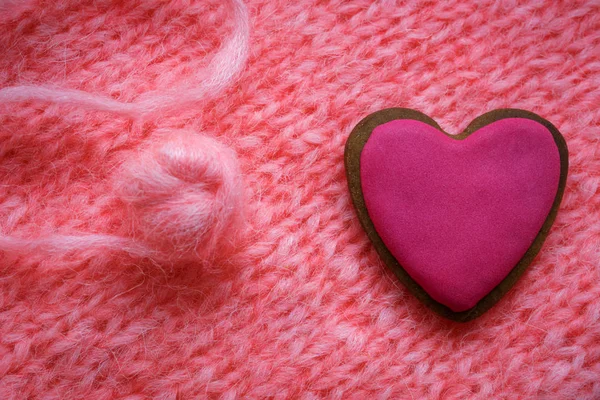 Pão de gengibre rosa em forma de coração em um fundo de tecido de malha rosa — Fotografia de Stock