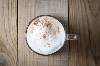Ahşap arka plan üstten görünüm üzerinde tarçın ile cappuccino kahve fincan