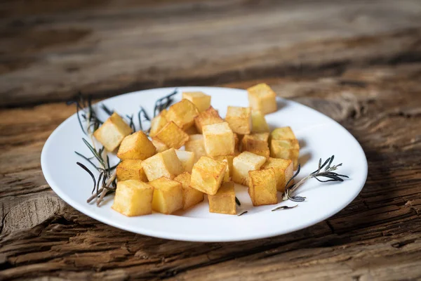 Cubes de pommes de terre frites au romarin sur fond de bois — Photo