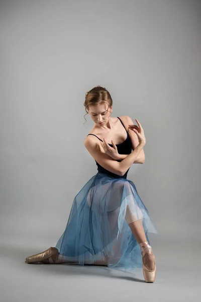 Linda menina bailarina dançando em uma saia azul exuberante no fundo cinza no estúdio — Fotografia de Stock