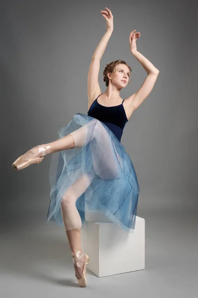 Mooie balletdanser poseren in Studio op witte blokjes en grijze achtergrond in Pointe-schoenen en een weelderige licht blauwe rok — Stockfoto