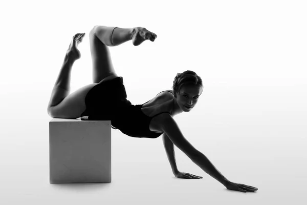 Graceful dancer performs the deflection standing on the bridge silhouette on a light background — Stock Photo, Image