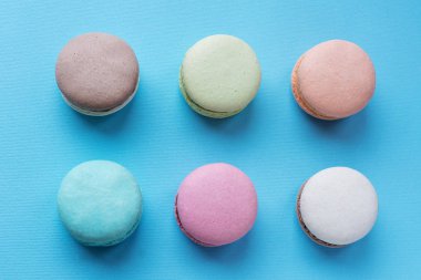 Mavi arka plan üzerinde renkli tatlı macarons