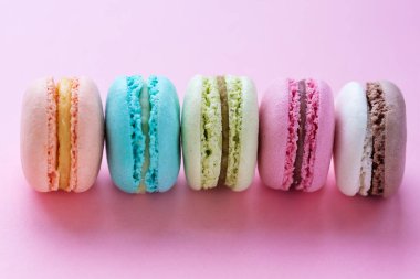 Pembe bir arka plan üzerinde renkli tatlı macarons