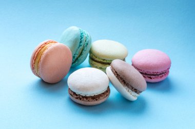 Mavi arka plan üzerinde renkli tatlı macarons