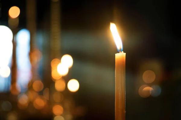 Bougie dans l'église sur un fond flou de bougies et de rayons de la fenêtre — Photo