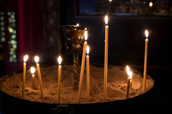 Brennende Kerzen in der Kirche, die in einer Sandschale stehen — Stockfoto