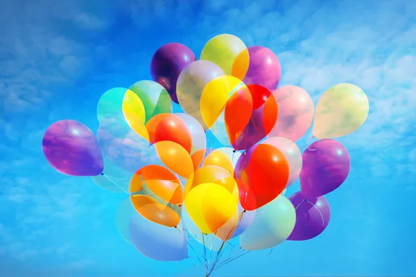 Mavi gökyüzü arka plan çoklu pozlama üzerinde çok renkli balonlar