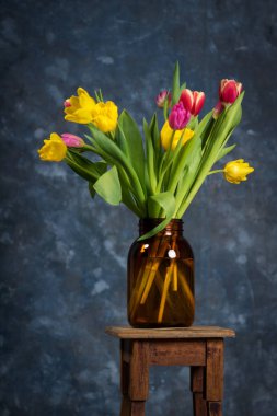 güzel mavi bir arka plan üzerinde cam vazoda kırmızı ve Sarı Lale buketi