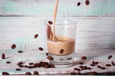 Krema Likör bir cam cam içine dökülür. kahve çekirdekleri ahşap arka plan üzerinde. sprey