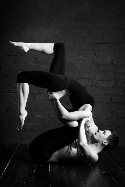 Young Caucasian yoga couple. Sporty handsome man supports and kisses a slender girl. yoga concept shows strength, trust and love. black-white