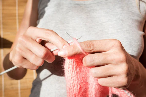Mädchen stricken rosa Schal. Nahaufnahme von Hand und Stricknadeln. Prozess des Strickens. Sonnenlicht — Stockfoto