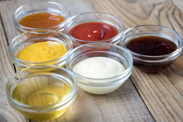 блюдо из различных соусов в стеклянных чашах в форме треугольника
