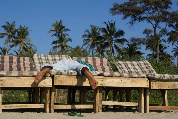 Индусы спят на шезлонге под пальмами босиком. расслабиться Стоковая Картинка