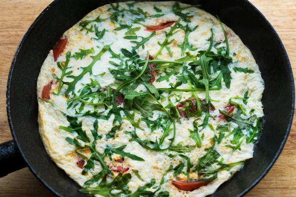 bir tavada sıcak roka ve domates ile yeni pişirilmiş omlet