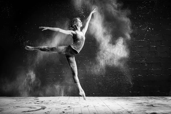 Beautiful ballet dancer dancing barefoot on black background in a cloud of dust — Stock Photo, Image