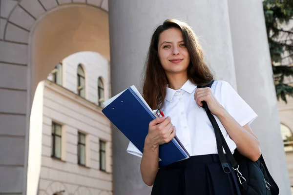 Menina estudante segurando uma pasta nas mãos, estudante universitário, uma escola , Fotos De Bancos De Imagens