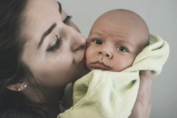 Portret matki gospodarstwa i całując jej dziecko Zdjęcie Stockowe