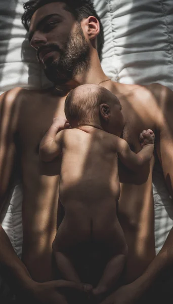 Noworodek leżąc na ciele ojca w łóżku Obrazek Stockowy